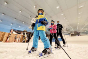  A man with two kids, lined up one after another, all dressed in ski gear, in a snow-filled area 