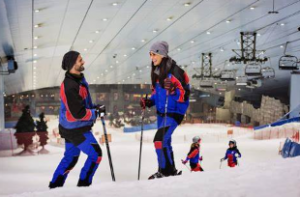  A couple in ski gear sharing a laugh amidst a snow-covered landscape, with two skiers visible in the background. 