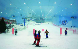 View of an indoor snow park with numerous skiers enjoying the various activities. 