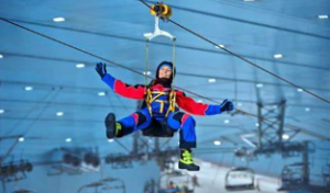 A woman in full gear riding the Snow Bullet ride in the air, securely fastened by a harness. 