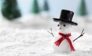  A tiny snowman in a snow-covered field wearing a black hat on its head and a red scarf around its neck. 
