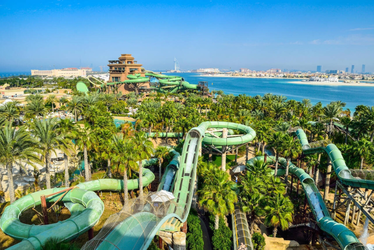 A wide shot of Aquaventure Waterpark Dubai featuring long slides and a private beach in the backdrop. 