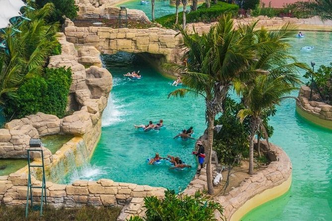 A group of people floating individually in Lazy River surrounded with palm trees and stone tunnels