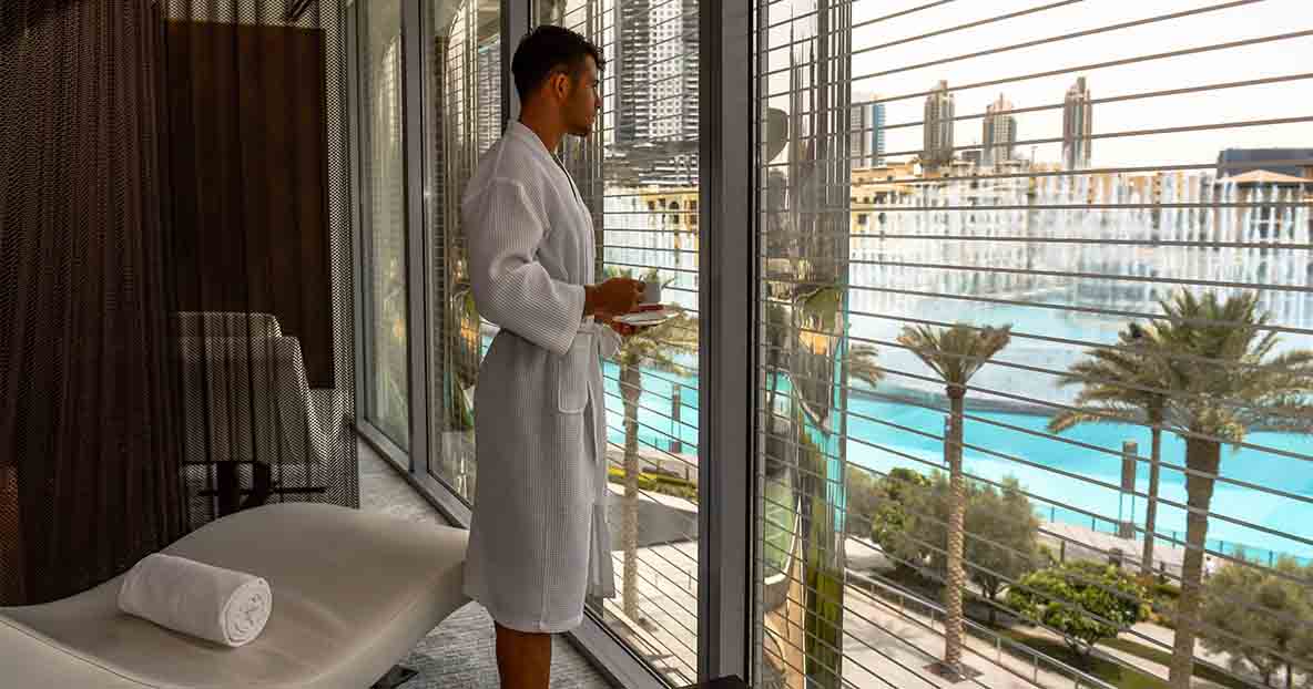 A man looking out of the Burj Club window in a robe after a relaxing spa