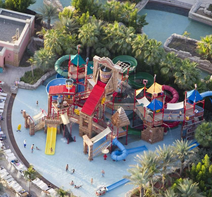 An aerial view of a colourful play area featuring water slides, tunnels and splash zones