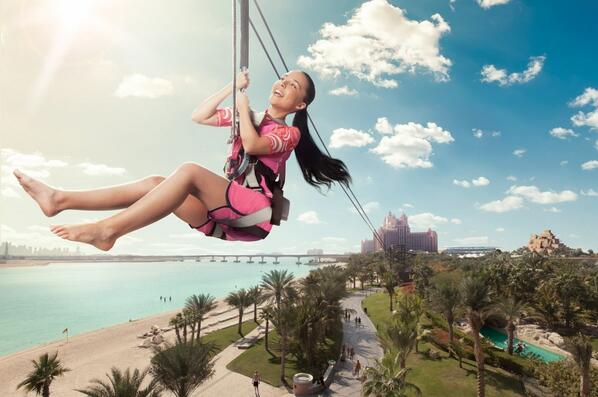 A little girl is suspended in air as she glides through the zipline overlooking the waterpark